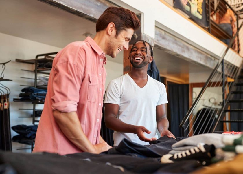 Smiling Sales Assistant Helping Male Customer To Buy Clothes In Fashion Store