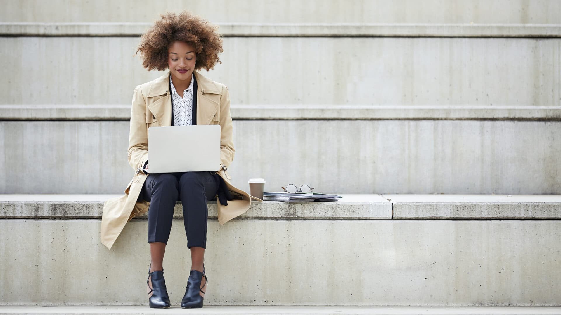 Young businesswoman using laptop on steps