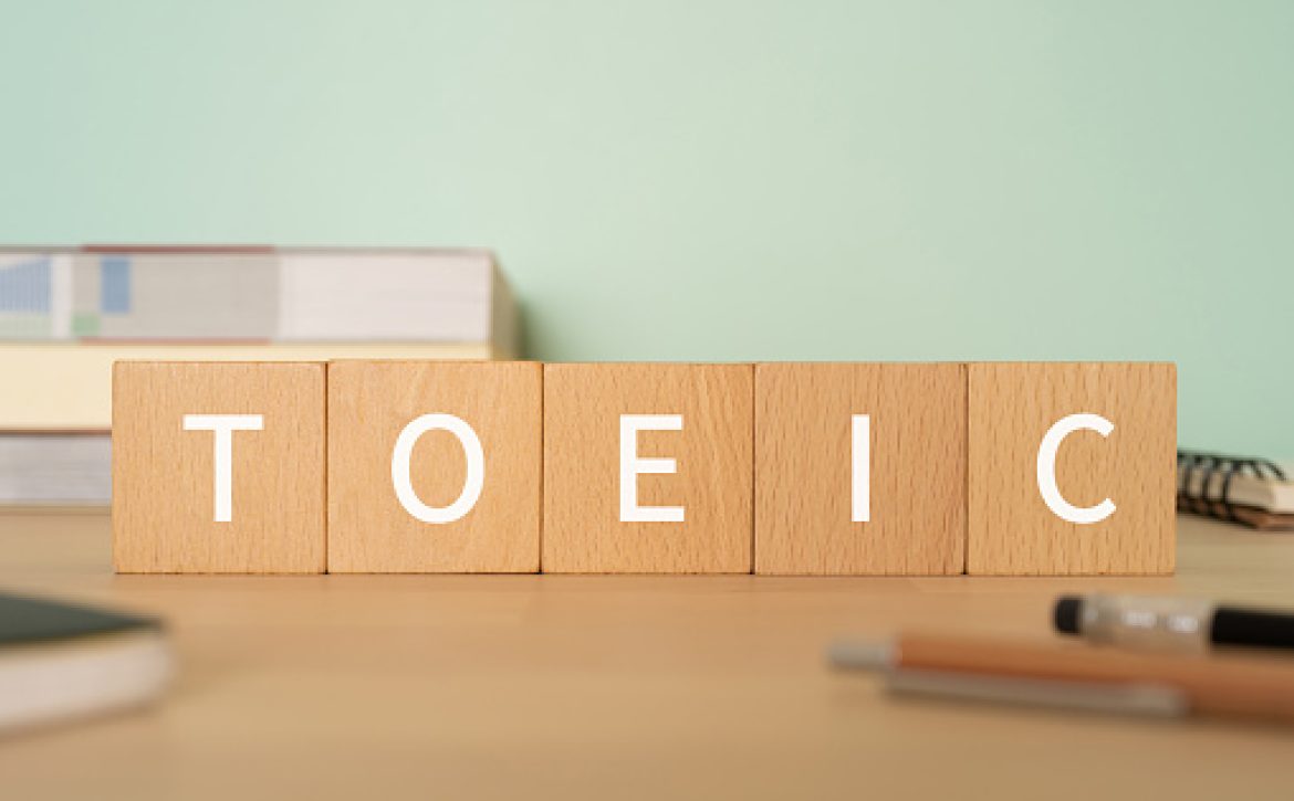 Wooden blocks with "TOEIC" text of concept, pens, notebooks, and books.